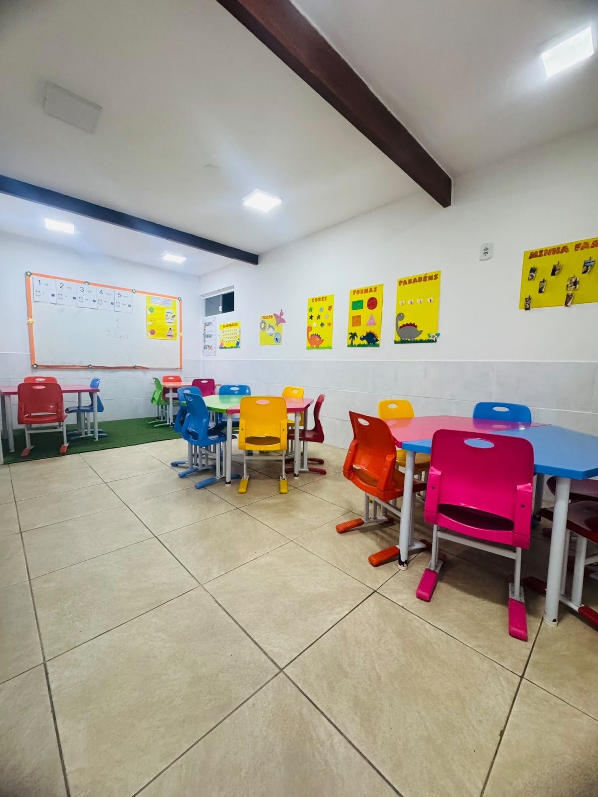 Sala de atividades da Espaço Baby com mesinhas coloridas e painéis pedagógicos